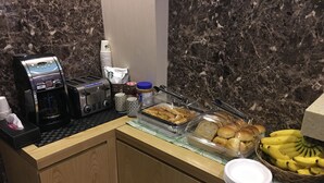 A breakfast bar with a coffee maker, toaster, and food containers.