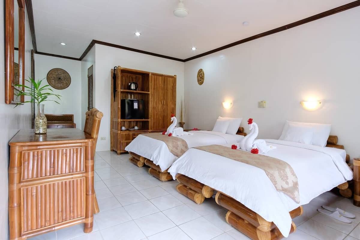 Habitación de hotel con dos camas, un armario de madera, un escritorio y un espejo.