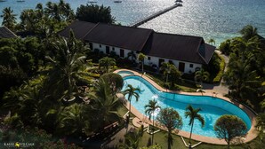 A resort with a swimming pool, palm trees, and a view of the ocean.