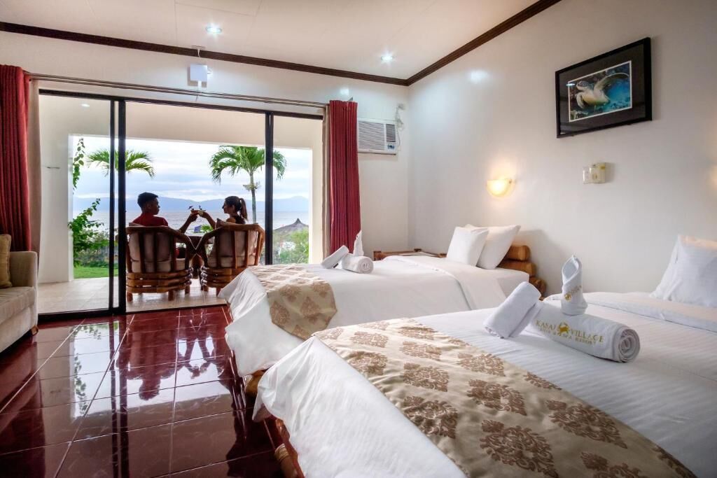 A hotel room with two beds, a balcony with a view, and a dining area with two people.