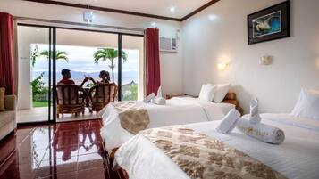 A hotel room with two beds, a balcony with a view, and a dining area with two people.