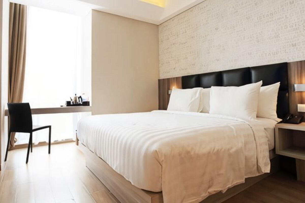 Une chambre d’hôtel avec un grand lit, un bureau et une chaise.