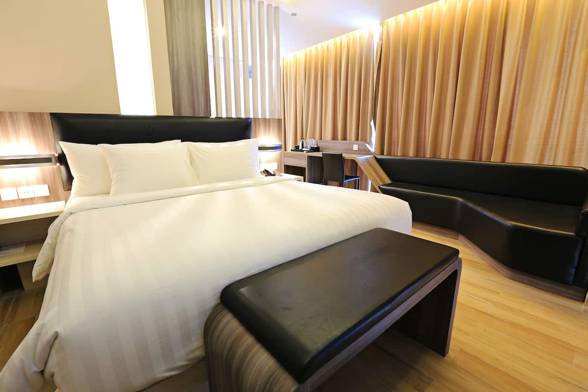 Una habitación de hotel moderna con una cama grande, un escritorio, un sofá y un banco.