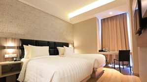 Una habitación de hotel con una cama grande, mesitas de noche, un escritorio y una silla.