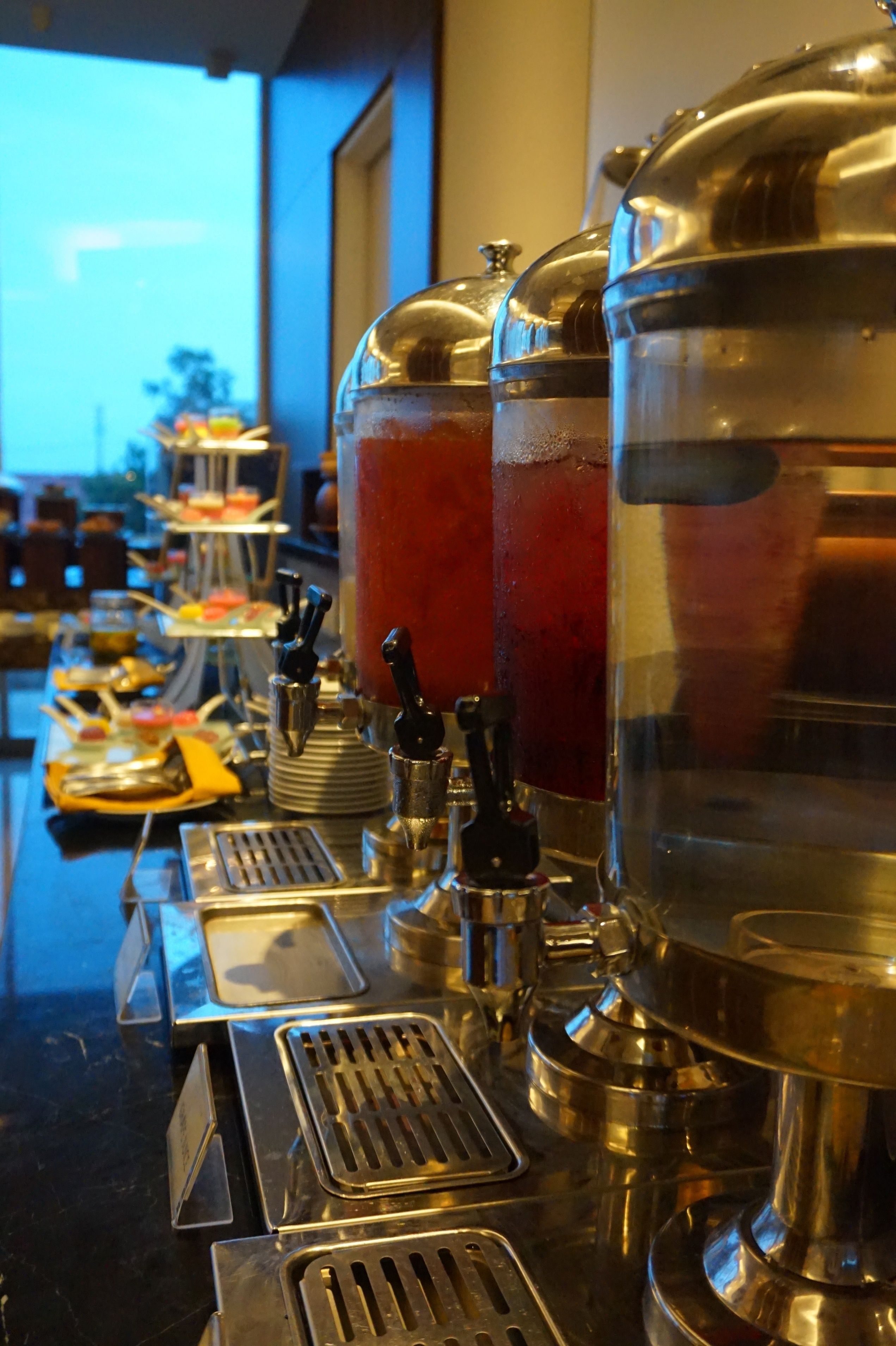 A buffet setup with multiple beverage dispensers and serving trays.