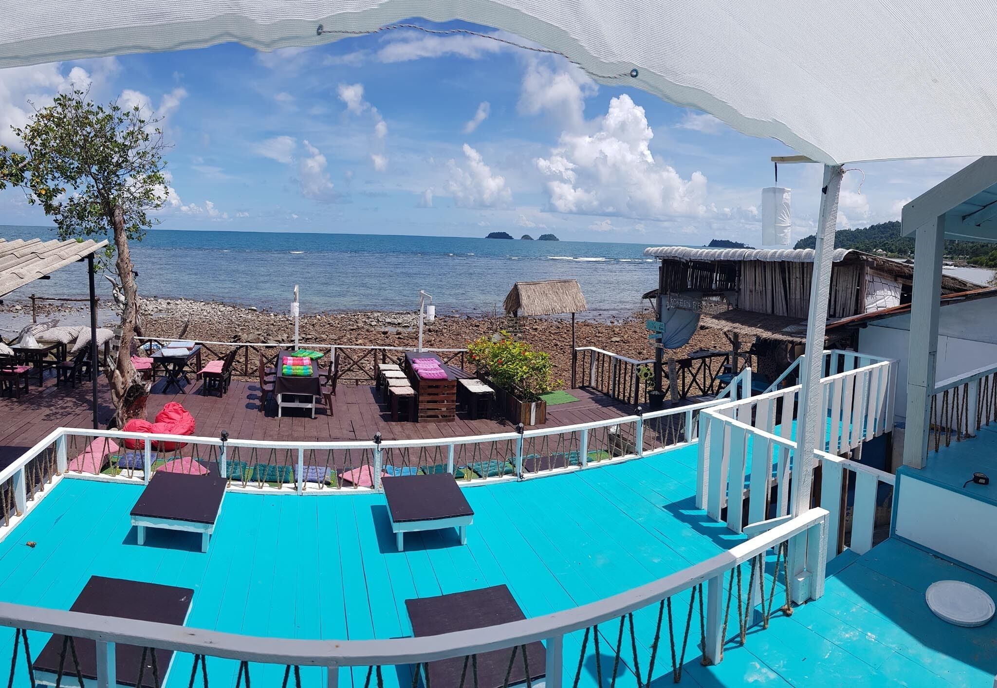 A beachside terrace with a pool, lounge chairs, and a view of the sea.