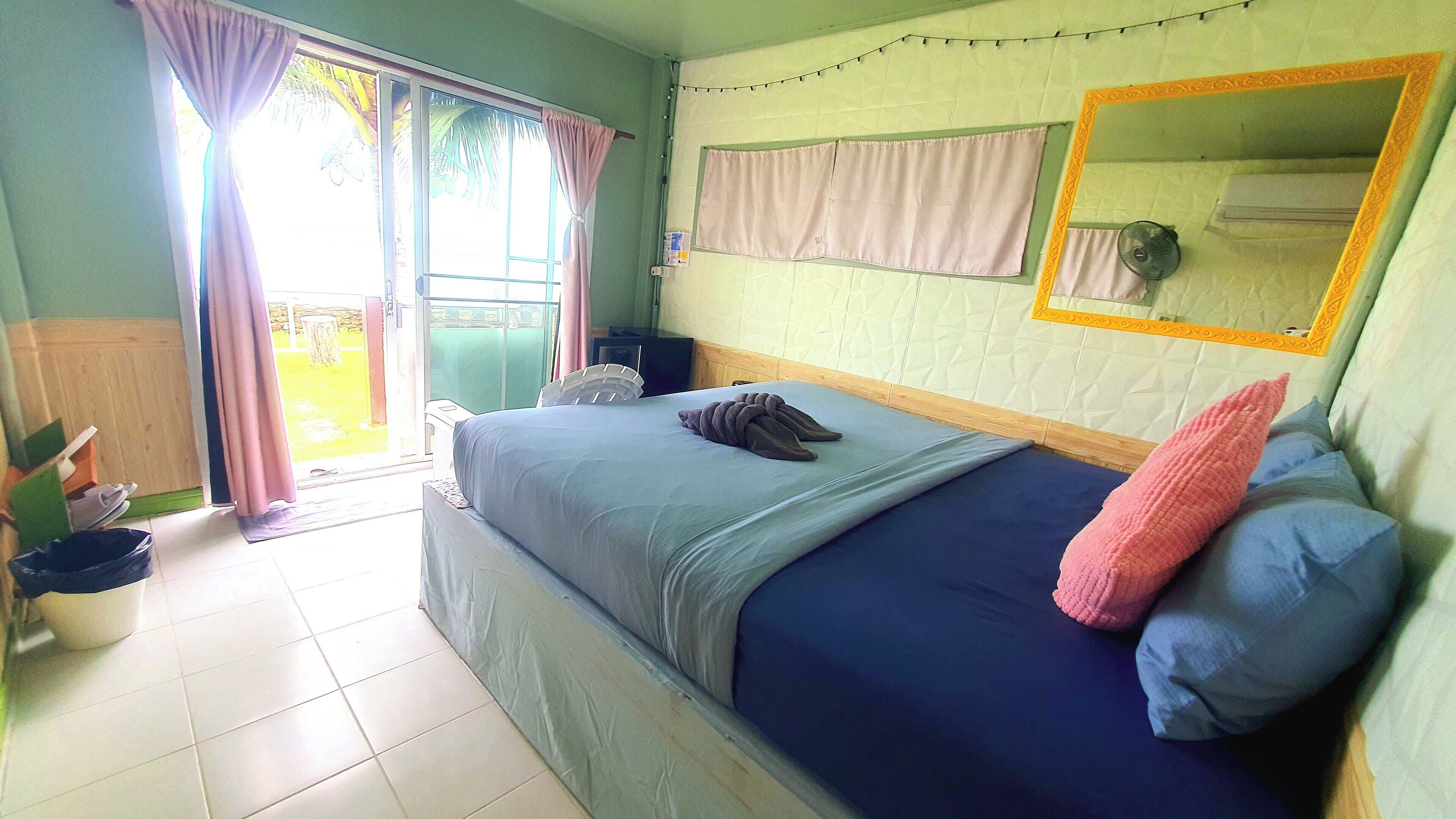 Een slaapkamer met een bed, een spiegel en een raam met gordijnen.
