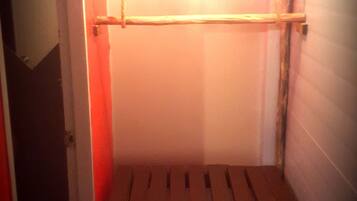 Una habitación pequeña, tenuemente iluminada, con un banco de madera y una sola silla.