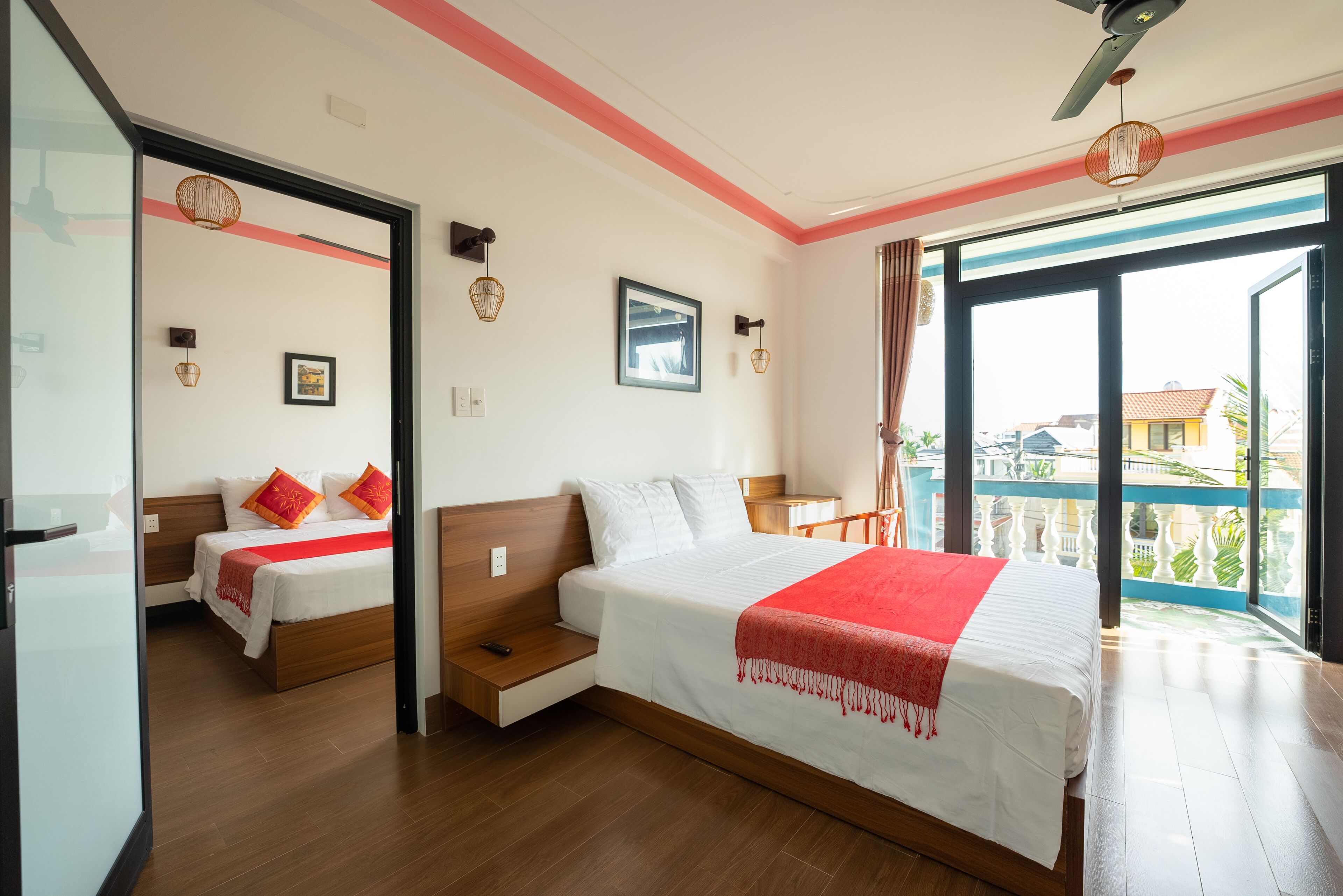 A hotel room with a large bed, a smaller bed, a desk, and a balcony with a view.