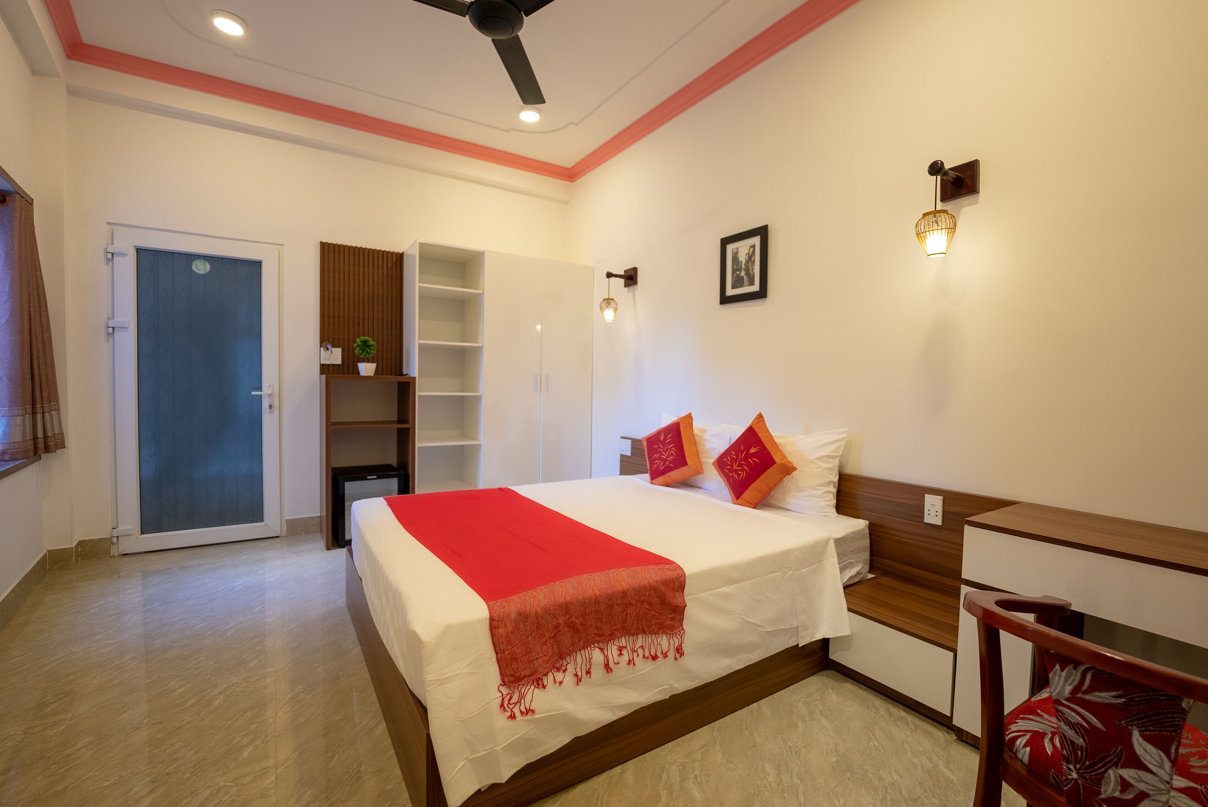 A bedroom with a bed, a desk, a chair, a wardrobe, and a ceiling fan.