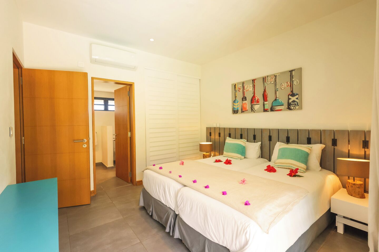 A hotel room with a bed, two bedside tables, a door, and a wall with a decorative painting.
