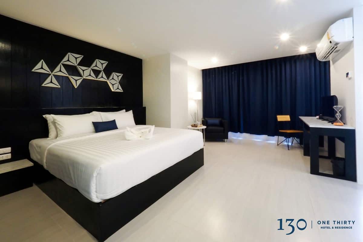 Une chambre d’hôtel moderne avec un grand lit, un bureau et un rideau foncé en arrière-plan.