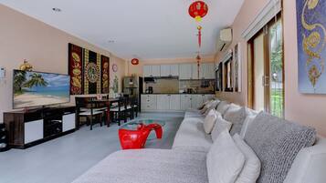 A living room with a sofa, a TV, and a dining area with chairs and a table.