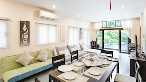 Un comedor con una mesa dispuesta para cuatro personas, un sofá y vistas a zonas verdes.