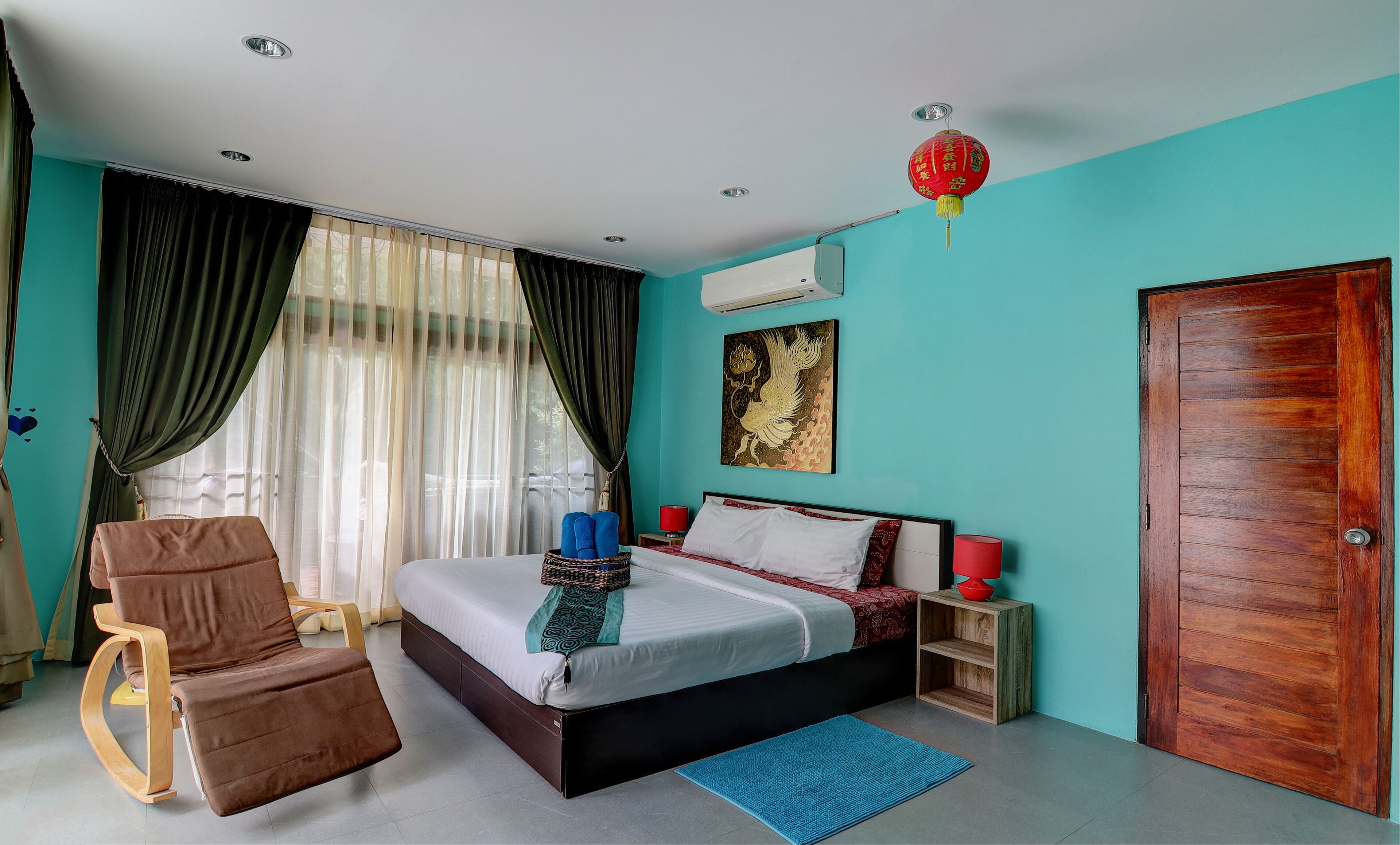 A bedroom with a bed, a chair, a bedside table, a red lantern, and a wooden door.