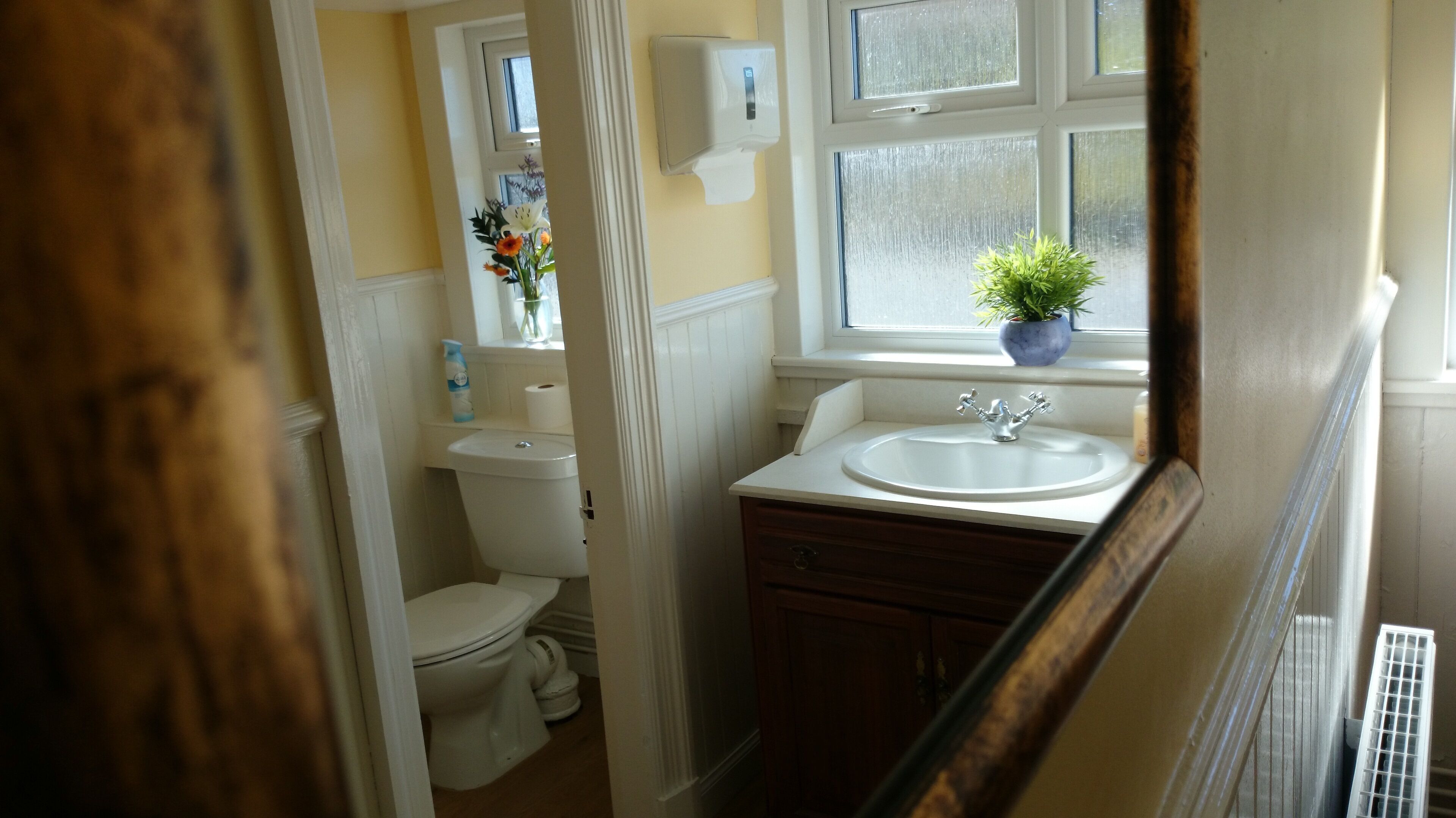 A bathroom with a toilet, sink, and window.