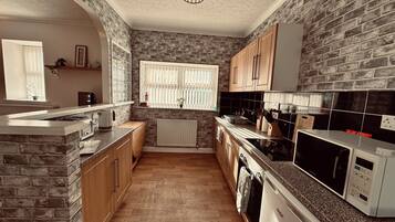 A kitchen with brick walls, wooden cabinets, a granite countertop, a built-in stove, a microwave, and a dishwasher.