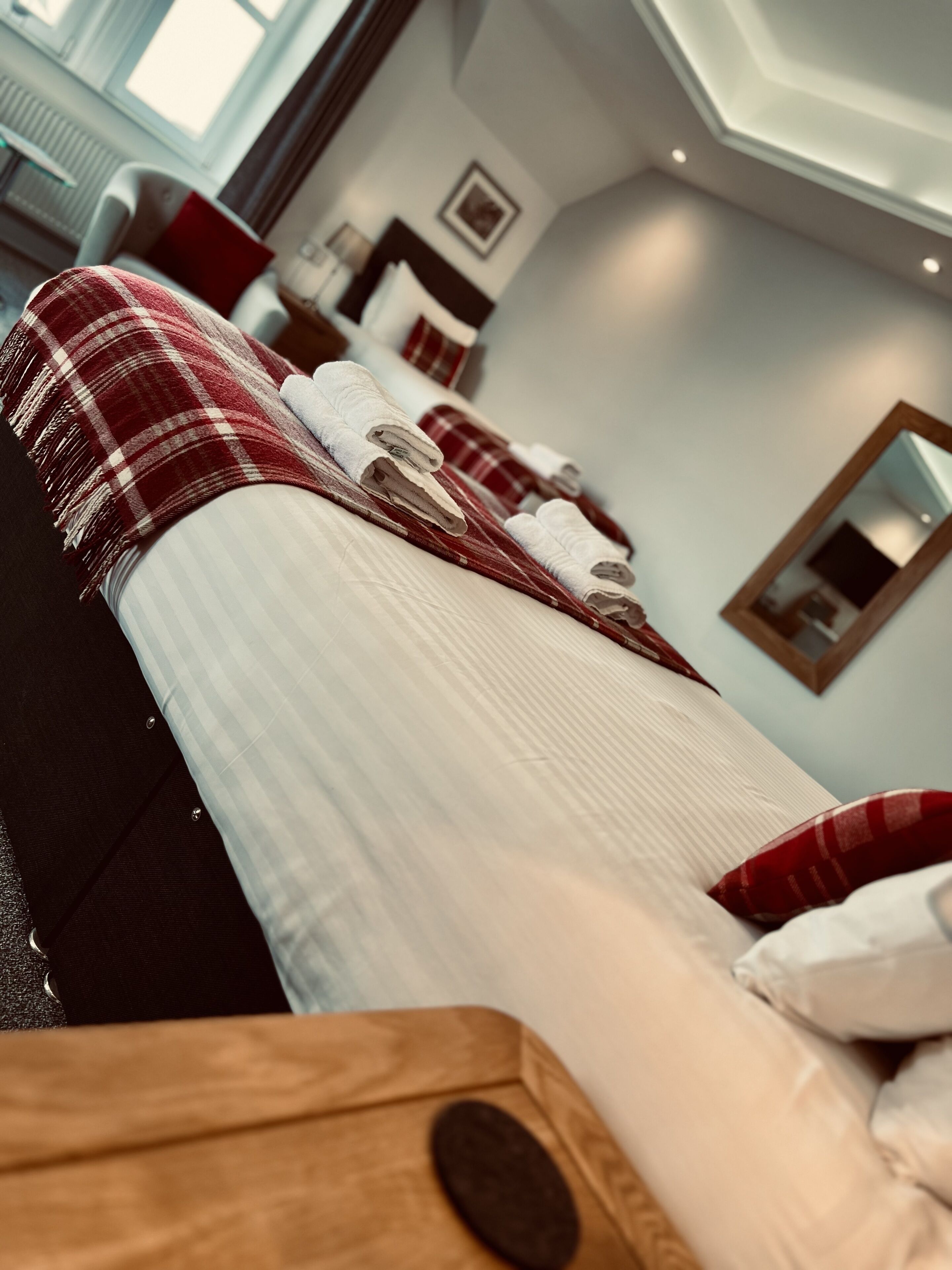 A hotel room with a bed, a wooden headboard, and a red and white checkered blanket.