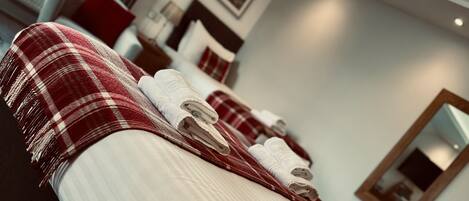 A hotel room with a bed, a wooden headboard, and a red and white checkered blanket.