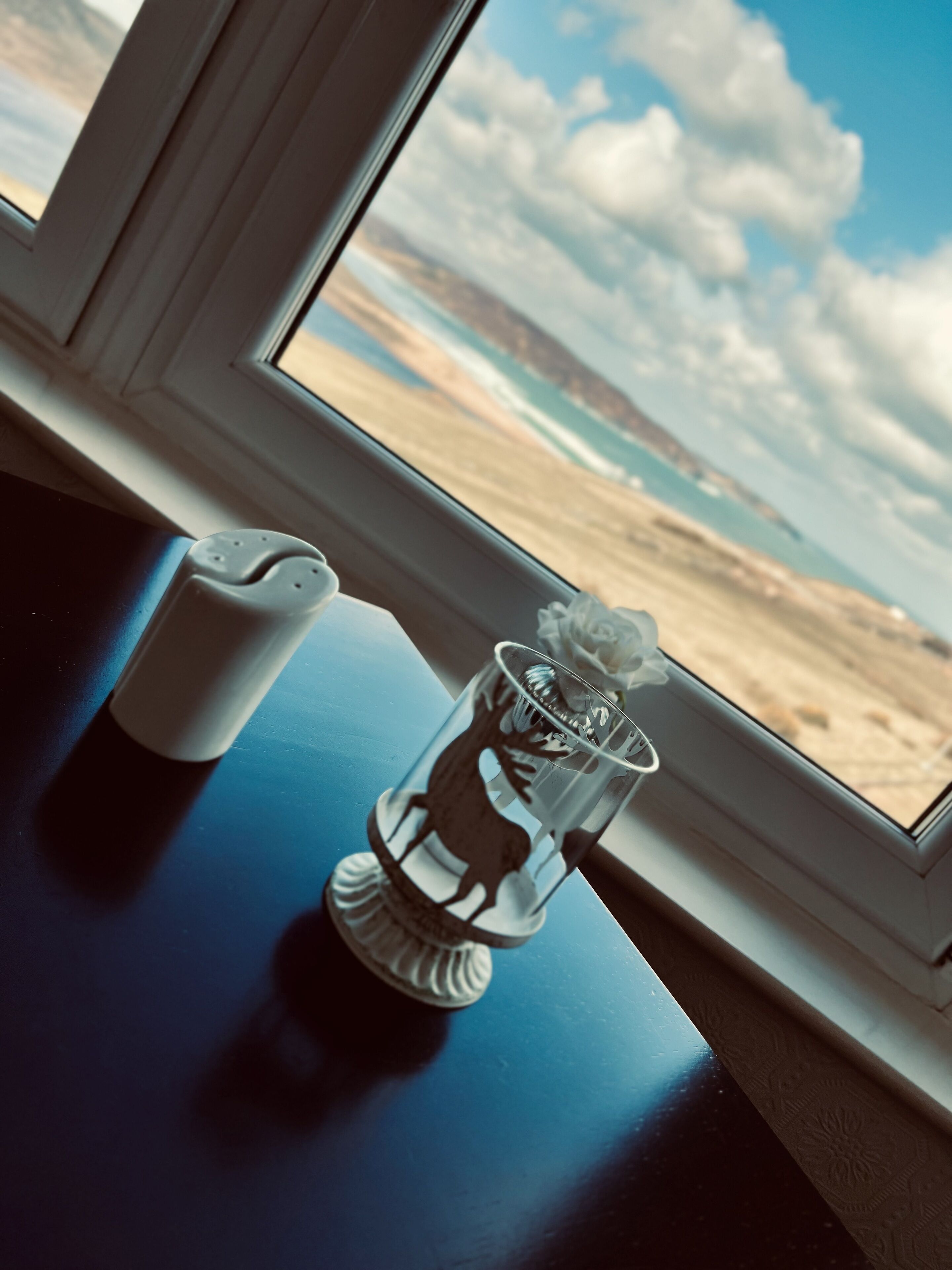 Une table avec un salier et un porte-bougie en verre orné de la silhouette d’un cerf.