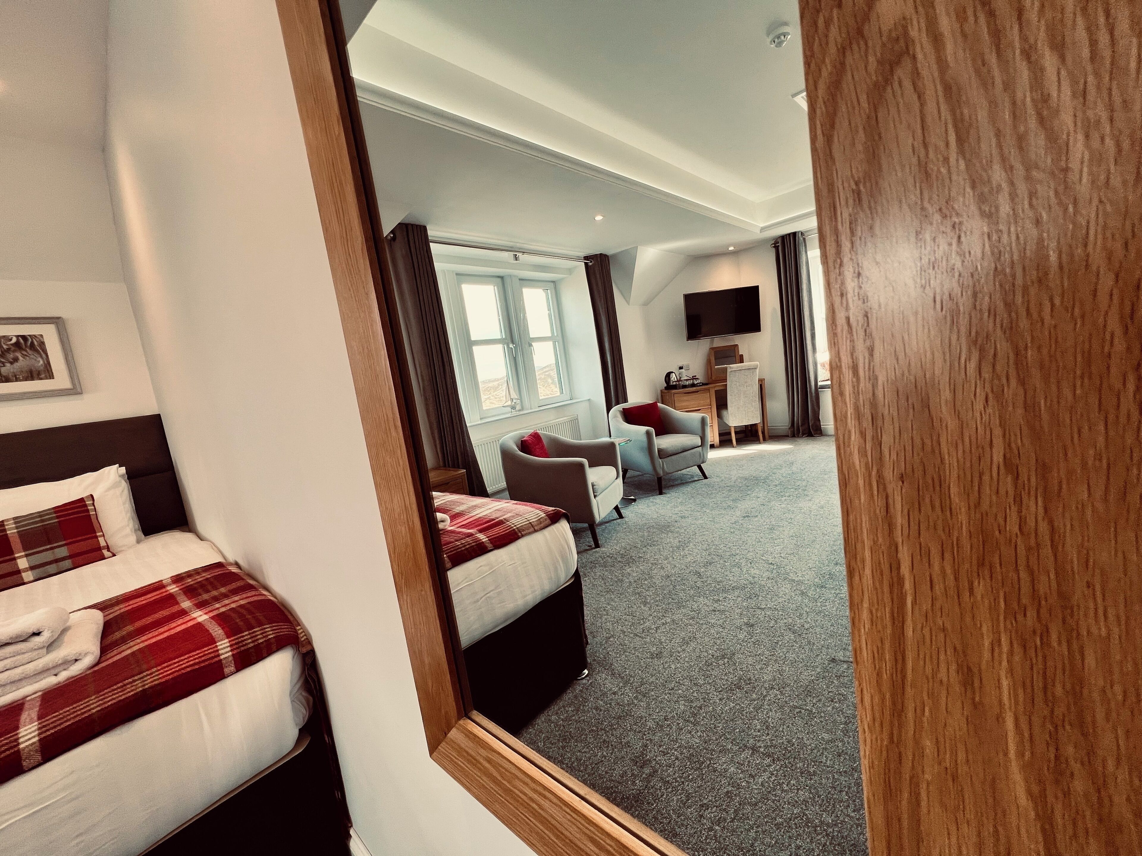A hotel room with a bed, a desk, a chair, and a TV.