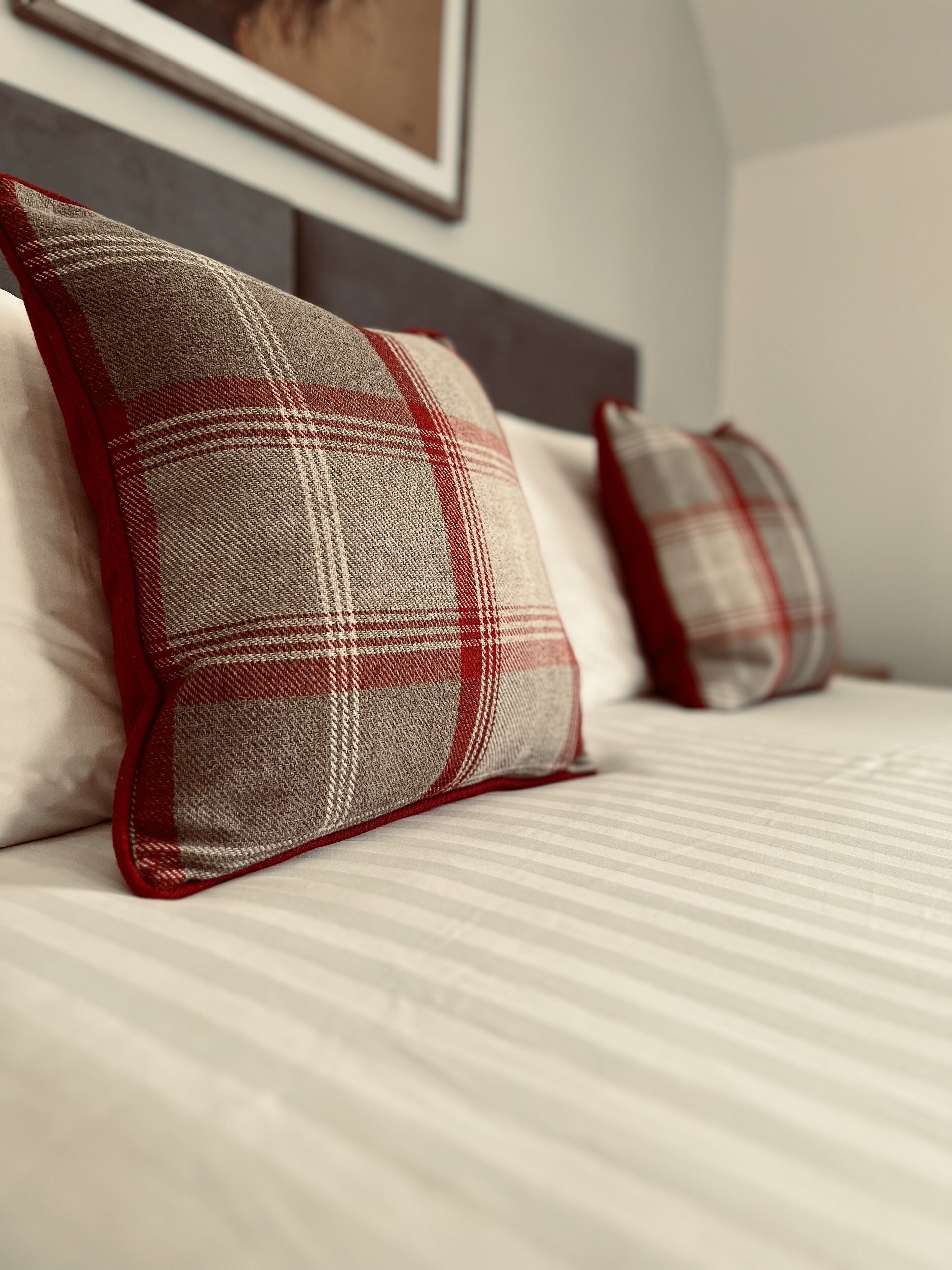 A bed with two pillows and a framed picture on the wall.