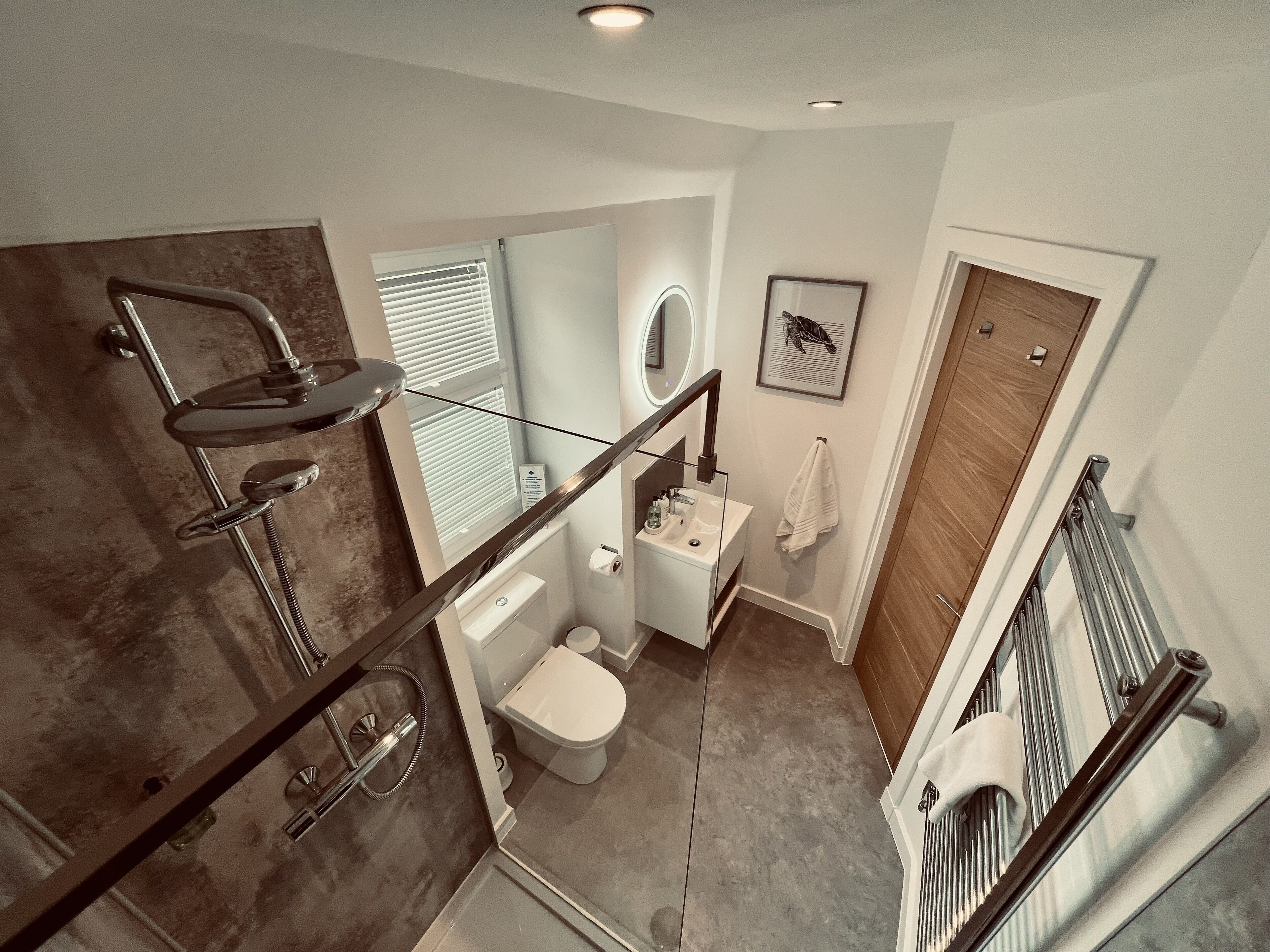 A modern bathroom with a glass shower enclosure, a toilet, and a sink.