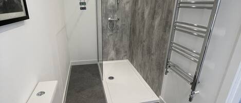 Un baño moderno con ducha, inodoro y toallero.