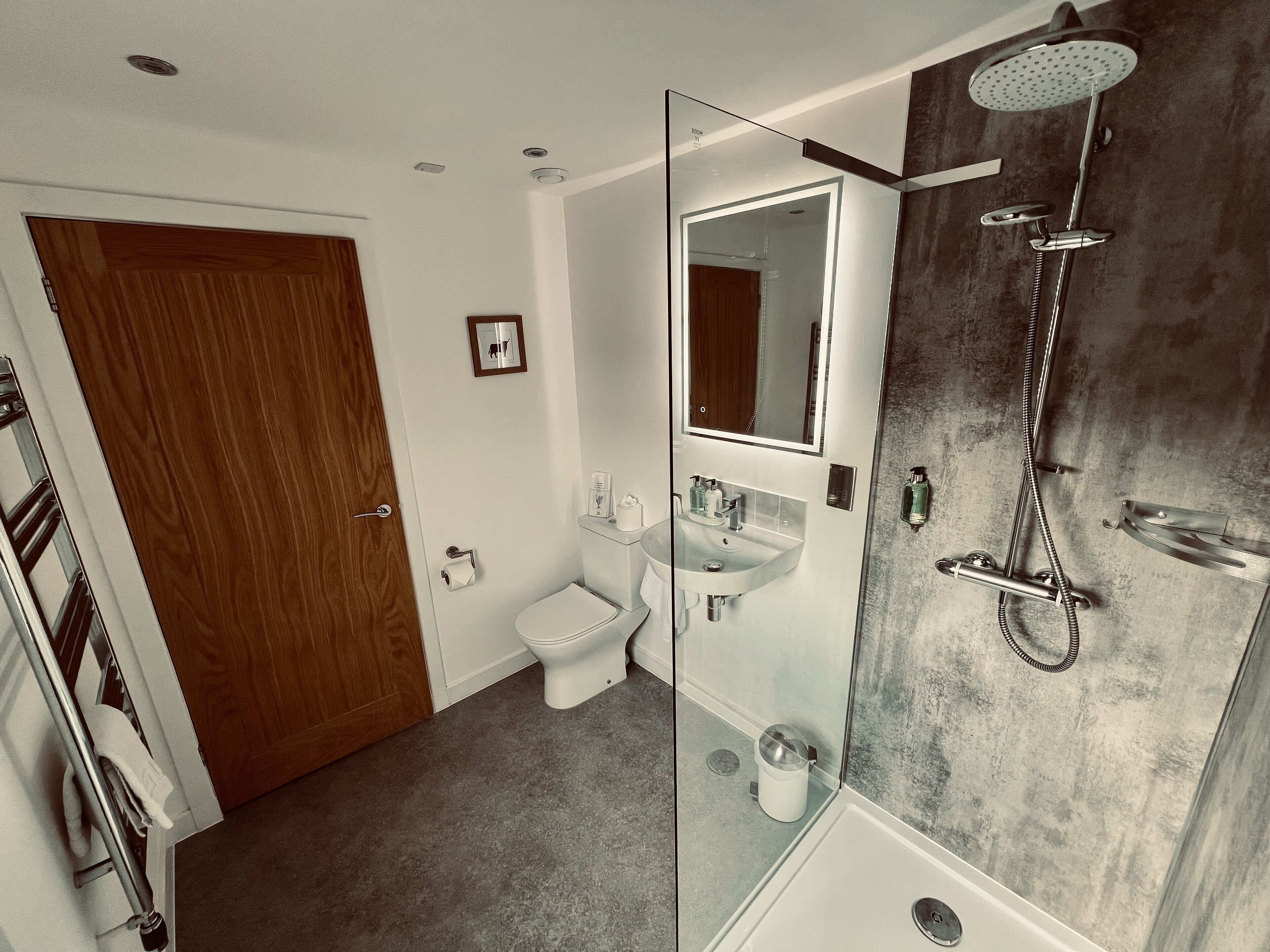 Een moderne badkamer met toilet, wastafel en douche.