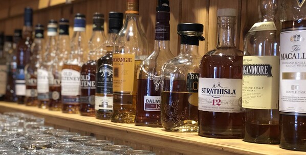 A variety of whiskey bottles on a wooden shelf.