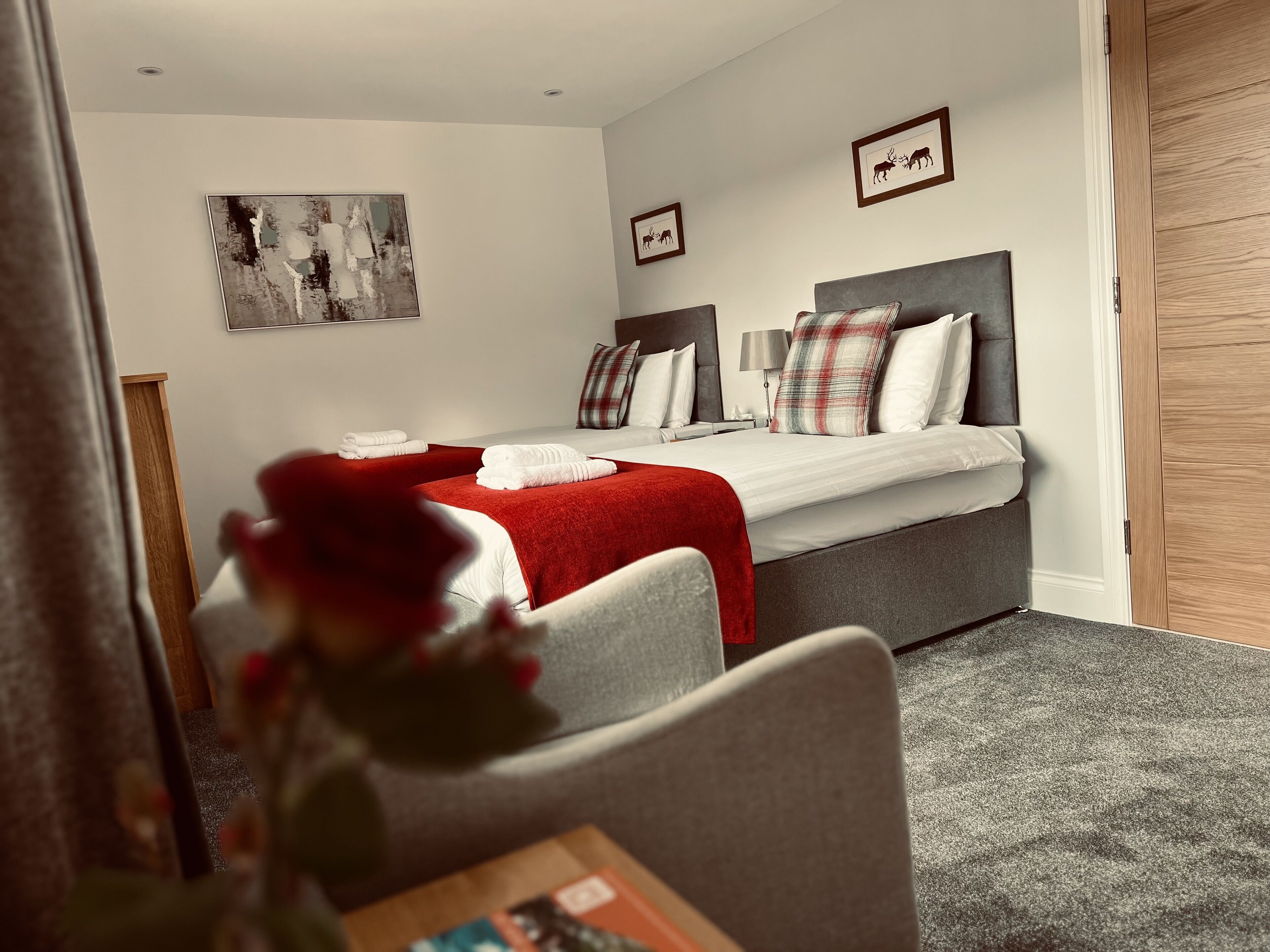 Habitación de hotel con dos camas, un cuadro abstracto grande y una puerta de madera.