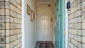 A hallway with a plaid carpet, a white door, and brick walls. - Apartment 32 (York)