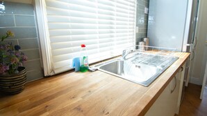 A kitchen with a wooden countertop, a stainless steel sink, and a window with blinds. - Apartment 32 (York)