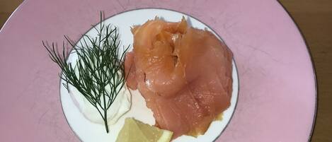 Lautasella on savulohta, tilliä ja sitruunaviipale, ja lautanen on vaaleanpunainen.