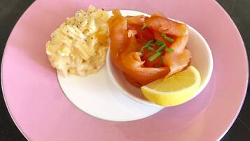 Un plato de salmón y puré de patatas sobre un plato rosa.