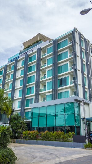A multi-story hotel with a modern design, featuring a prominent "Unique Regency" sign at the top.