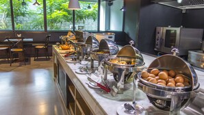 Un'area buffet con diversi contenitori per cibo, posate e un'area salotto con sedie e tavoli.