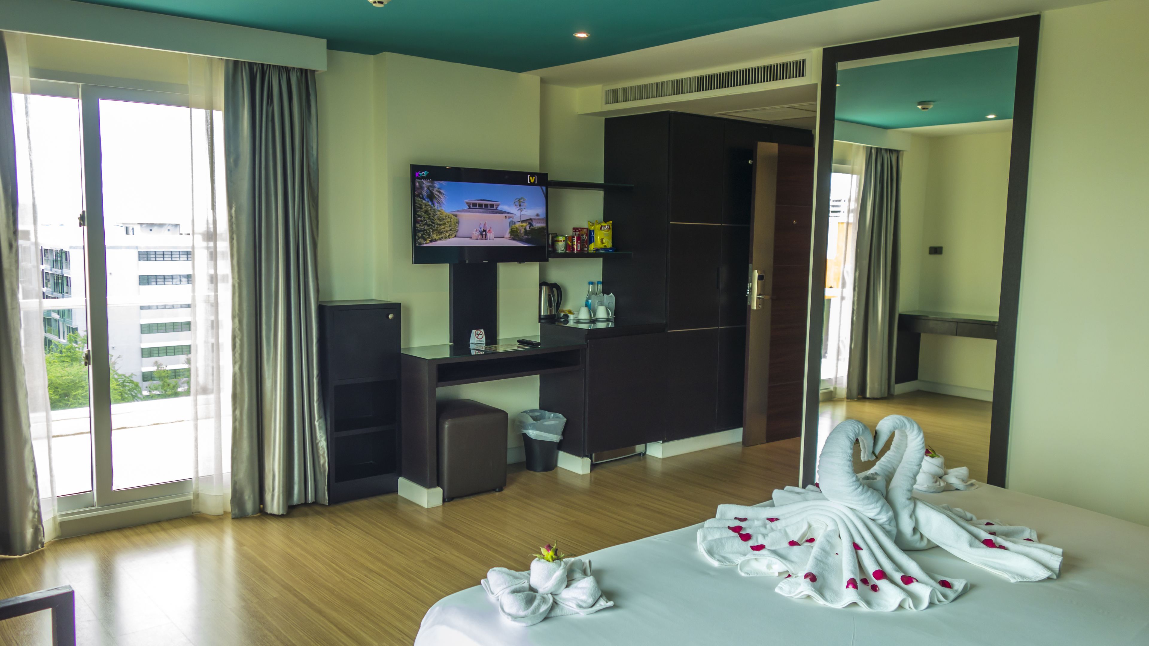 Quarto de hotel com cama, televisão, escrivaninha e vista para edifícios.
