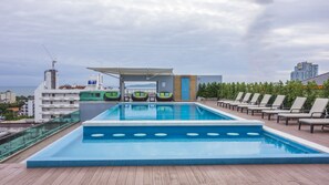 A rooftop swimming pool with lounge chairs and a covered seating area.