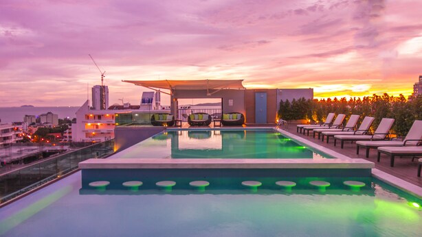 Una piscina a sfioro con lettini e vista sul tramonto.