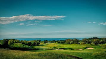 Un campo de golf con vistas despejadas al océano e indicadora en el hoyo 18.