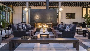 Un espacio lounge moderno al aire libre con sofás, una mesa central y una chimenea.