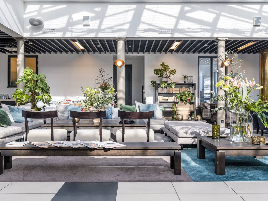 Un salon moderne avec un canapé, des fauteuils, une table basse et des plantes en pot.
