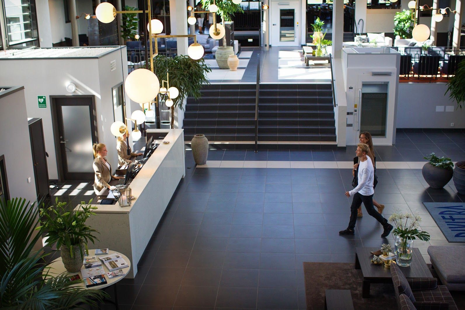 Eine geräumige Lobby mit einer Rezeption, Sitzbereichen und einer Treppe zu den oberen Etagen.
