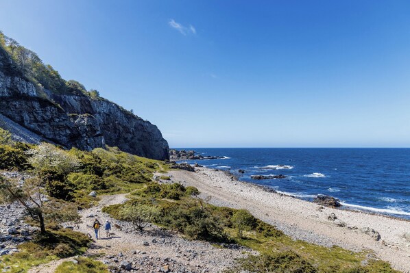 A coastal landscape with rocky terrain, a clear sky, and a view of the ocean. - Hotel Riviera Strand (Bastad)