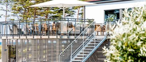 An outdoor seating area with tables and chairs, a staircase, and a railing.