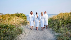 Un sendero que conduce a la playa, con cuatro personas vestidas de blanco.