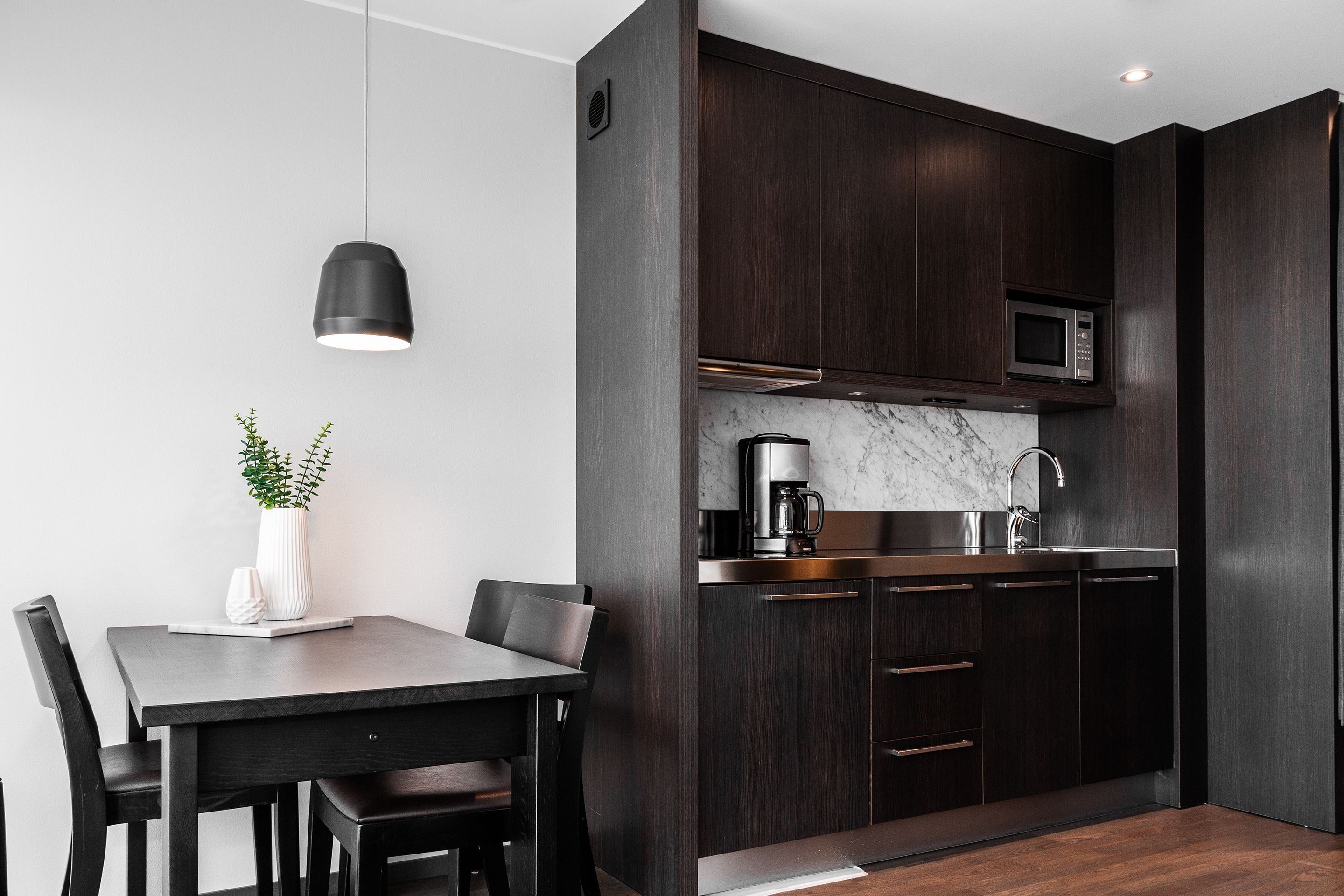 Una cocina moderna con armarios de madera oscura, un microondas de acero inoxidable y una encimera de mármol.