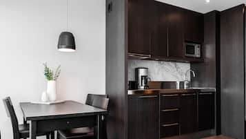 A modern kitchen with dark wood cabinets, a stainless steel microwave, and a marble countertop.