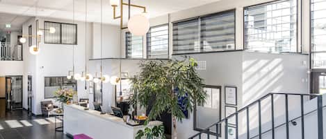 A modern reception area with a desk, a staircase, and large windows.